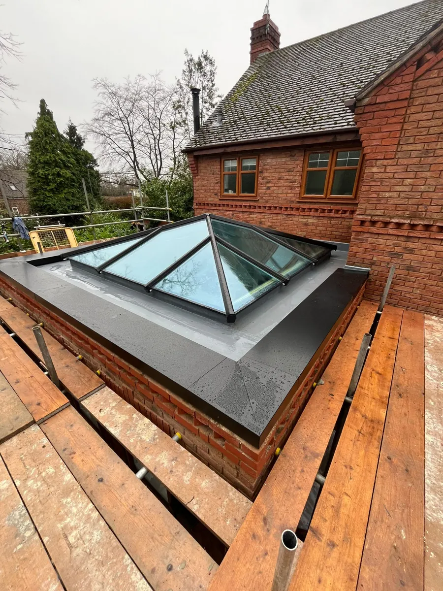 Completed anthracite aluminium roof lantern on a fibreglass flat roof, photographed from the scaffold